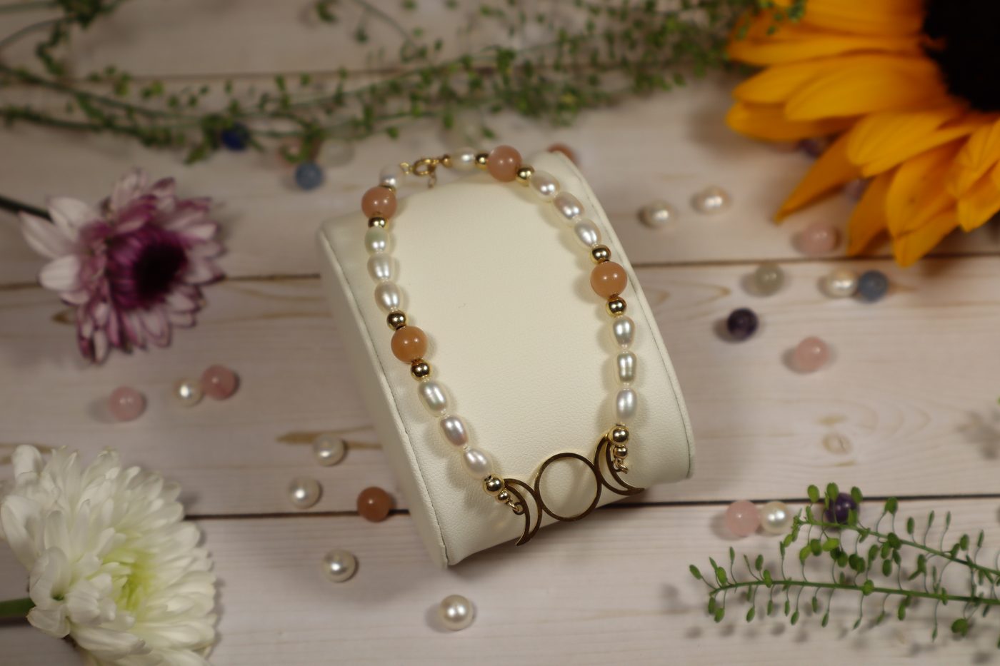 Handcrafted pearl and moonstone bracelet with gold-filled beads on a jewelry display stand